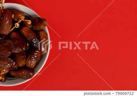 Cropped image of a plate full of fresh mediterranean delicious and tasty dates. Red background, copy space 79808722