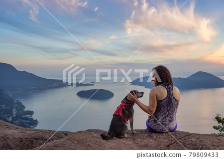 Woman hiking on top of a mountain with a dog 79809433