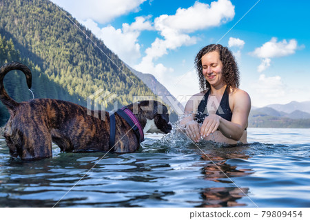 Caucasian Woman swimming in a lake with dog 79809454