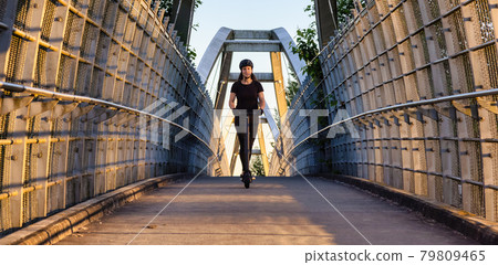 Caucasian Adult Woman riding an electric scooter on a path 79809465