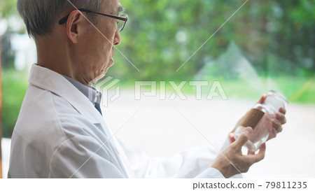 Senior male scientist looking at a bottle of medicine Pharmacist Senior male scientist looking at a bottle of medicine Pharmacist 79811235