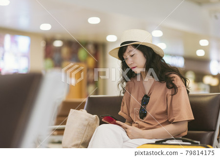Travel girl using phone while waiting at airport Travel girl using phone while waiting at airport 79814175