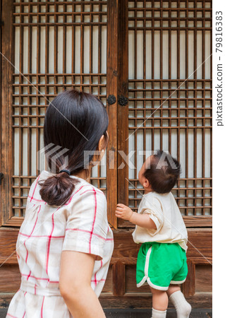 Baby opens the door to the Hanok with his mother 79816383
