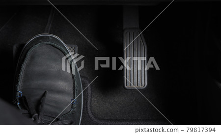 Man foot and accelerator and brake pedal inside the car or vehicle and copy space which black color leather shoe stepped on it for speed up or control automobile pace power. Automobile Driving concept 79817394