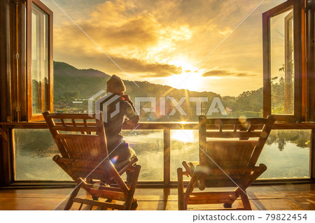 young alone woman watching lake view at coffee shop in the morning sunrise, Ban Rak Thai village, Mae Hong Son province, Thailand. Travel concept 79822454