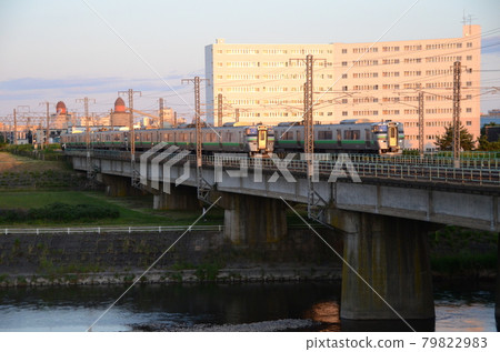 733 series train passing by on the Toyohira River bridge in the evening 733 series train passing by on the Toyohira River bridge in the evening 79822983