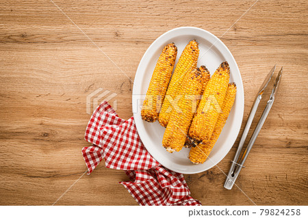 Grilled corn on the cob on wooden table, top view Grilled corn on the cob on wooden table, top view 79824258