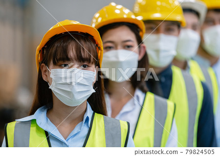 Teamwork engineering in uniform wear hardhat and protection mask at workshop industrial factory. 79824505