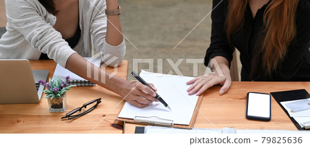 Two business colleagues checking financial documents together at meeting room. 79825636