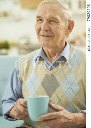 Smiling elderly man relaxing at home with a cup of hot tea Smiling elderly man relaxing at home with a cup of hot tea 79829298