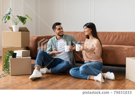 Happy man and woman drinking coffee sitting on floor Happy man and woman drinking coffee sitting on floor 79831833