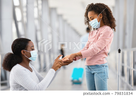 Black family traveling, lady using sanitizer on girl's hands Black family traveling, lady using sanitizer on girl's hands 79831834