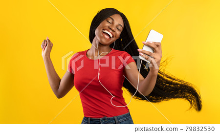African Woman Dancing Listening To Music Wearing Headphones, Yellow Background 79832530
