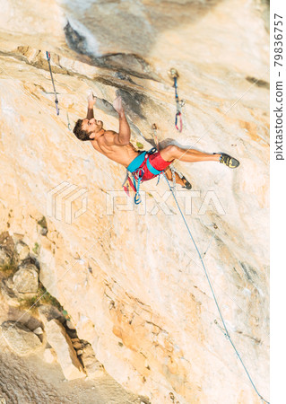 Rock climber holding on with both hands on the rock 79836757