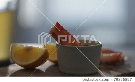 Crab leg meat on a olive board with sweet lemon and dip sauce on concrete countertop 79836897