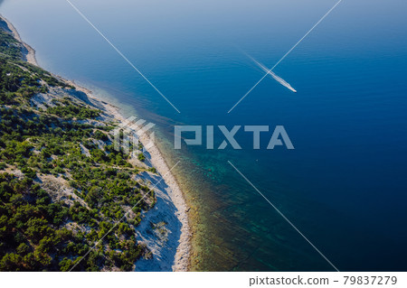 Coastline with blue sea, cliff with pine trees and motor boat. Summer day on sea. Aerial view Coastline with blue sea, cliff with pine trees and motor boat. Summer day on sea. Aerial view 79837279