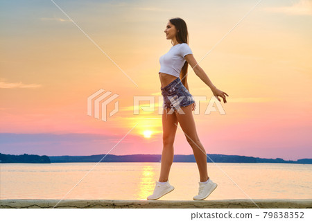 Happy young woman enjoys freedom in sunset time Happy young woman enjoys freedom in sunset time 79838352