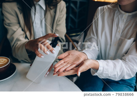 Women using an antibacterial antiseptic to disinfect at cafe. 79838666