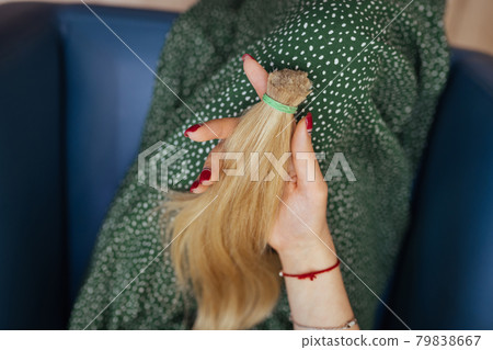 young woman holding her freshly cut long brown hair in pony-tails 79838667