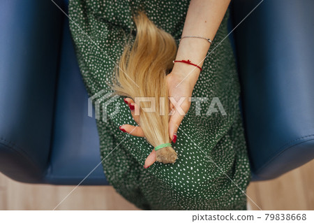 young woman holding her freshly cut long brown hair in pony-tails young woman holding her freshly cut long brown hair in pony-tails 79838668