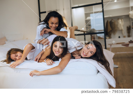 Positive young girls women friends indoors on bed at the hen party at home. 79838725