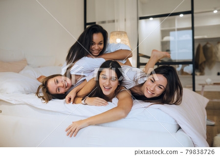 Positive young girls women friends indoors on bed at the hen party at home. 79838726