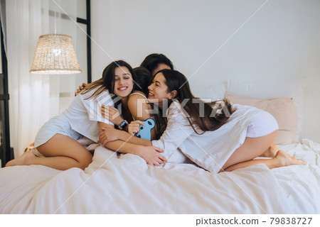 Positive young girls women friends indoors on bed at the hen party at home. Positive young girls women friends indoors on bed at the hen party at home. 79838727