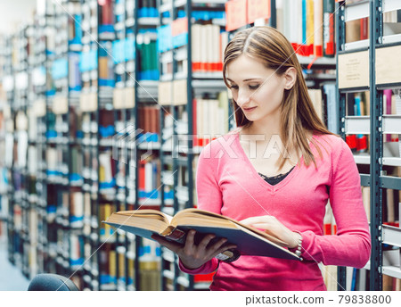 Student in college library reading a book Student in college library reading a book 79838800