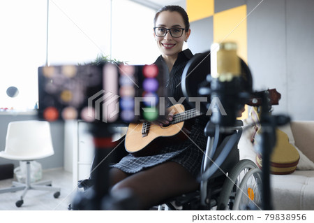 Smiling woman is recording guitar playing closeup Smiling woman is recording guitar playing closeup 79838956