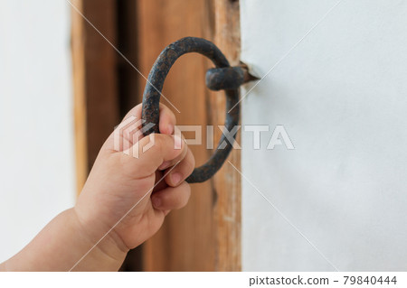 A baby's bare hands holding an old, rusty traditional doorknob A baby's bare hands holding an old, rusty traditional doorknob 79840444