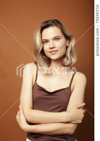 young pretty girl with blond hair posing cheerful on brown background, lifestyle people concept 79840556