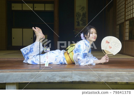 一個穿著漂亮浴衣的女人站在一座古老民居的門廊上 79841378