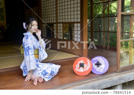 A woman in a beautiful yukata standing on the porch of an old folk house 79841514