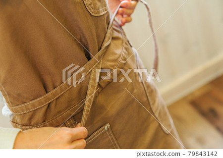 Woman tying an apron Woman tying an apron 79843142