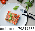 Top down view to piece of lasagna. Basil leafs 79843835