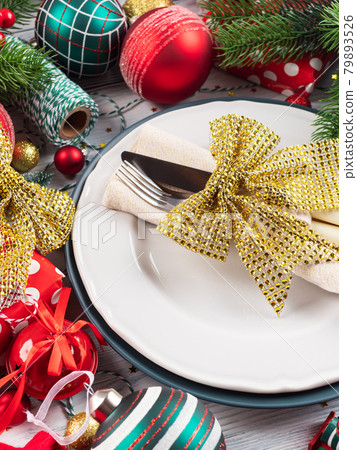 Christmas festive dinner table setting with decor and cutlery with golden bow Christmas festive dinner table setting with decor and cutlery with golden bow 79893526