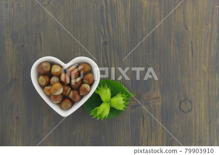 Fresh unshelled hazelnuts in a heart shaped dish 79903910