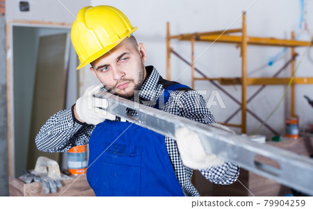 Repairman in helmet is looking at the level of the profile Repairman in helmet is looking at the level of the profile 79904259