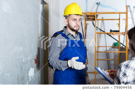 Worker in helmet with spatula is talking to client 79904456