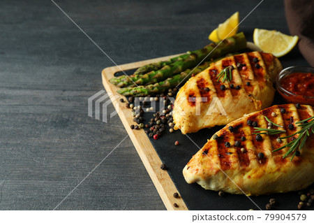 Board with grilled chicken and ingredients on dark wooden background 79904579