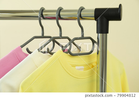 Wardrobe rack with sweatshirts against beige background 79904812