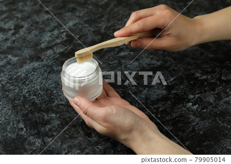 Female hand hold tooth powder and toothbrush on black smokey background 79905014