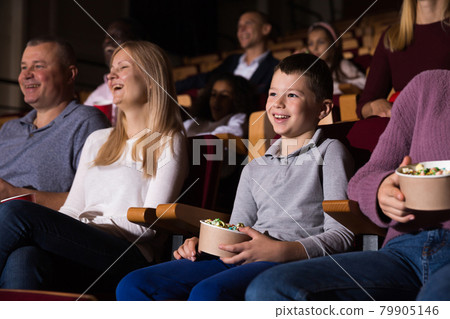 mother, father and their children sitting at comedy in auditorium 79905146