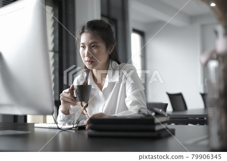 Businesswoman is watching online webinar with startup project on computer pc while drinking coffee at office. 79906345