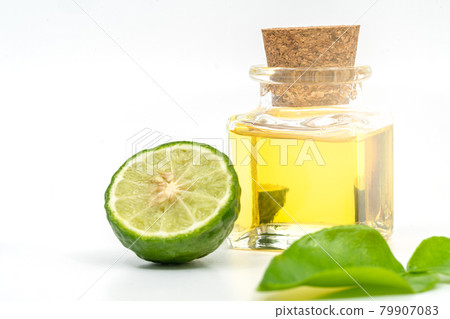 Beautiful packshot of Bergamot essential oil in a small glass bottle with cork, fresh bergamot fruit, and green leaf on white background. Blank space on the bottle for label design branding. 79907083
