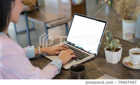 A businesswoman typing on laptop with empty screen at her workplace. A businesswoman typing on laptop with empty screen at her workplace. 79907487