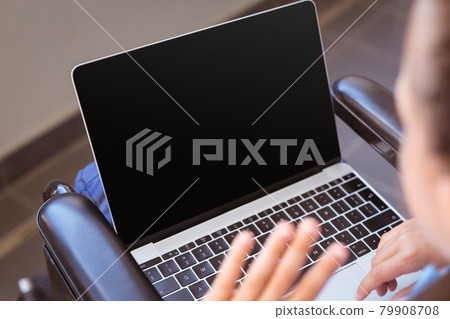 Disabled caucasian schoolgirl sitting in wheelchair using laptop, copy space on screen Disabled caucasian schoolgirl sitting in wheelchair using laptop, copy space on screen 79908708