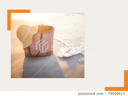 Photograph of hat over a bag and flip flops at the beach against grey background Photograph of hat over a bag and flip flops at the beach against grey background 79909613