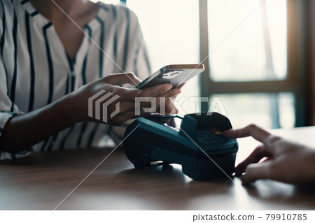 A woman paying bill by online banking application on her smartphone at shopping mall. A woman paying bill by online banking application on her smartphone at shopping mall. 79910785