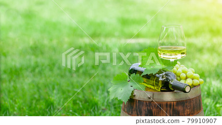 Wine bottle, glass with white wine and grape on old barrel Wine bottle, glass with white wine and grape on old barrel 79910907